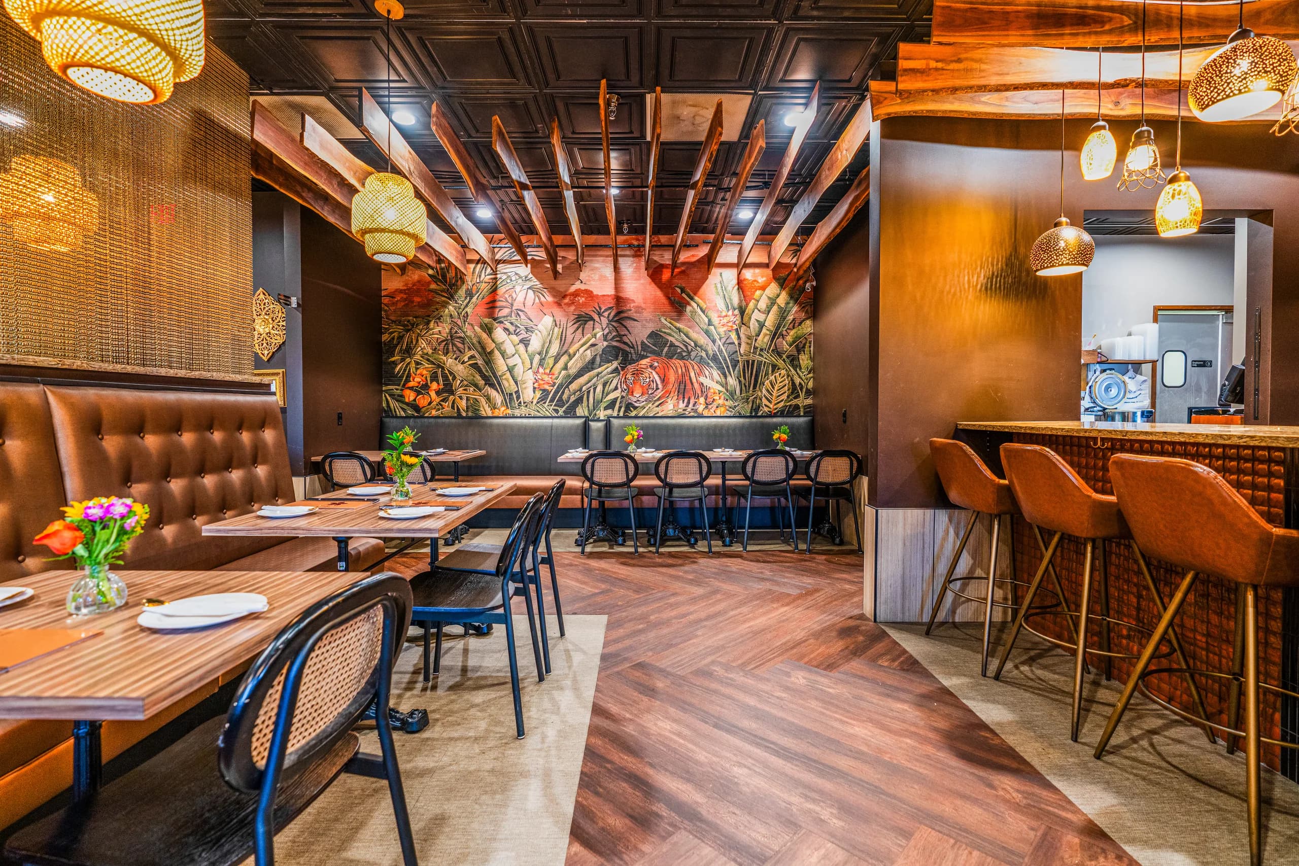 Leela Thai's dining room: rattan lanterns, live-edge beams, and the tiger jungle mural